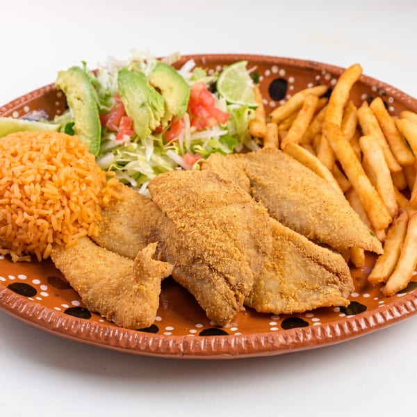 Fried fish fillets, french fries, rice, and salad with avocado on a decorative plate.